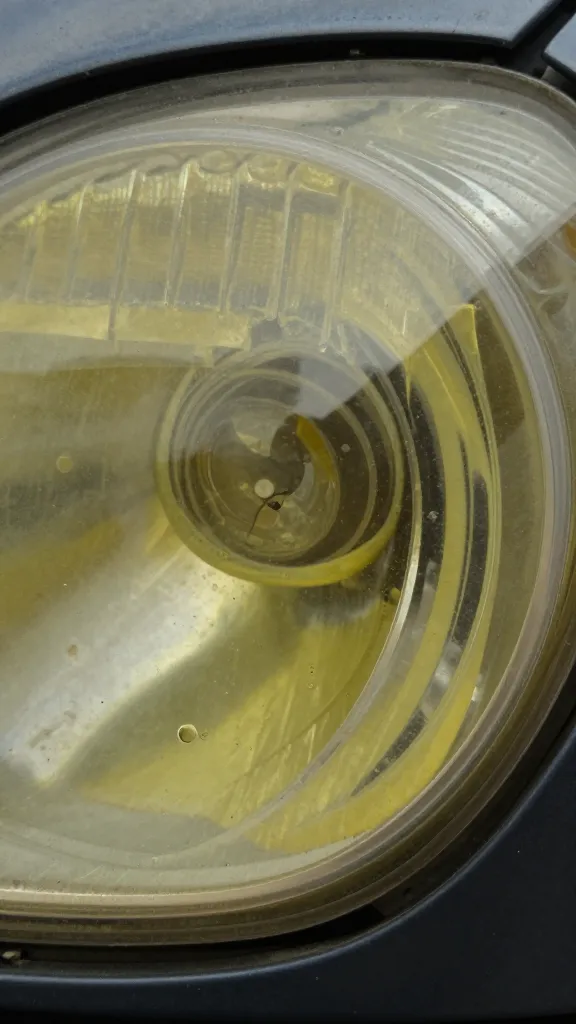 closeup of oxidized car headlight lens showing yellow haze
